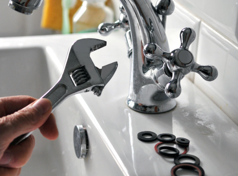worker with a plumbing tool fixing a platinum faucet